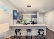 Thumbnail 5 of 27 - A kitchen with a white countertop and black bar stools.