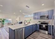 Thumbnail 6 of 27 - A modern kitchen with blue cabinets and stainless steel appliances.