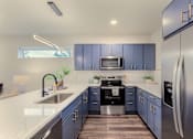 Thumbnail 7 of 27 - A modern kitchen with blue cabinets and stainless steel appliances.