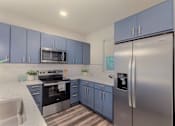 Thumbnail 8 of 27 - A kitchen with blue cabinets and stainless steel appliances.