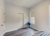 Thumbnail 14 of 27 - A room with a bed, chair, and sliding doors.