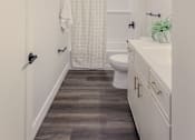 Thumbnail 15 of 27 - A white bathroom with a toilet, sink, and shower curtain.