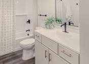 Thumbnail 16 of 27 - A white bathroom with a toilet, sink, and a mirror.