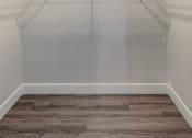 Thumbnail 25 of 27 - A room with a grey floor and white walls with clothes hangers.