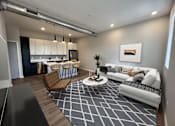 Thumbnail 5 of 50 - A modern living room with a kitchen in the background.