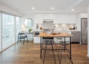 Thumbnail 1 of 13 - A modern kitchen with a dining table and chairs.