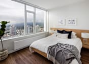 Thumbnail 5 of 13 - A bedroom with a large bed and a view of the city.