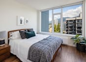 Thumbnail 6 of 13 - A bedroom with a large bed and a view of the city.