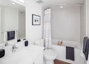 Thumbnail 8 of 13 - A white bathroom with a toilet, sink, and bathtub.
