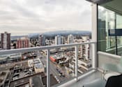 Thumbnail 9 of 13 - A balcony with a chair overlooking a cityscape.