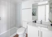 Thumbnail 10 of 13 - A white bathroom with a toilet, sink, and shower.