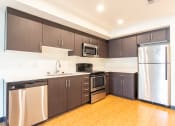 Thumbnail 3 of 15 - an empty kitchen with stainless steel appliances and wooden floors
