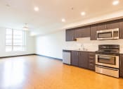Thumbnail 5 of 15 - an empty kitchen with wood flooring and stainless steel appliances