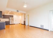 Thumbnail 4 of 15 - an empty living room with wood flooring and a kitchen