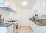 Thumbnail 6 of 25 - a kitchen with white appliances and granite counter tops