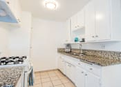Thumbnail 9 of 25 - a kitchen with white cabinets and granite counter top and a stove
