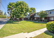 Thumbnail 15 of 22 - an apartment building with a lawn and trees in front of it