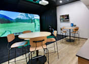 Thumbnail 35 of 107 - A room with a table, chairs, and a large screen displaying a mountainous landscape.
