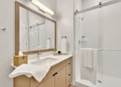 Thumbnail 57 of 107 - A bathroom with a sink, mirror, and shower.