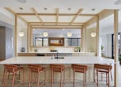 Thumbnail 34 of 107 - A kitchen with a white counter and brown stools.
