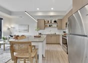 Thumbnail 77 of 107 - A modern kitchen with a stainless steel refrigerator and wooden chairs.