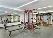 Thumbnail 19 of 107 - A gym with a variety of equipment including a squat rack and a bench.