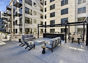 Thumbnail 7 of 107 - A patio area with a table and chairs is surrounded by apartment buildings.