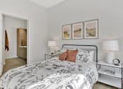 Thumbnail 74 of 107 - A bedroom with a large bed and a nightstand with a lamp on it.