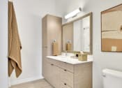 Thumbnail 69 of 107 - A white toilet sits in a bathroom with a wooden vanity and a mirror.