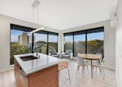 Thumbnail 100 of 107 - A modern kitchen with a large island and a view of the city.
