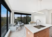 Thumbnail 94 of 107 - A modern kitchen with a large island and a view of the outdoors.