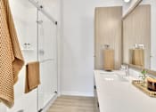 Thumbnail 79 of 107 - A bathroom with a white sink and a brown towel hanging on the shower rod.