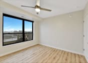 Thumbnail 89 of 107 - A room with a ceiling fan and a large window overlooking a cityscape.
