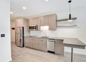 Thumbnail 48 of 107 - A modern kitchen with a refrigerator, microwave, and a countertop.