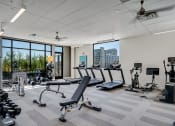 Thumbnail 7 of 24 - a gym with treadmills and other exercise equipment in a building with large windows