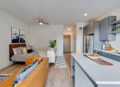 Thumbnail 19 of 24 - a living room with a yellow couch and a kitchen with a sink