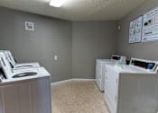 Thumbnail 11 of 13 - A room with two washing machines and a wall with flyers.