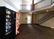 Thumbnail 13 of 13 - A vending machine is on the left of a hallway with a staircase on the right.