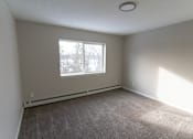 Thumbnail 8 of 13 - A room with a window and carpeted floor.