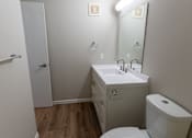 Thumbnail 10 of 13 - A white toilet sits next to a sink in a small bathroom.