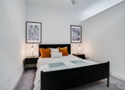 Thumbnail 3 of 24 - a bedroom with a bed and two nightstands with orange pillows