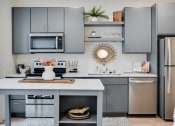 Thumbnail 23 of 24 - a kitchen with gray cabinets and stainless steel appliances and a white counter top