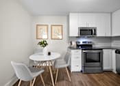 Thumbnail 23 of 53 - a kitchen with white cabinets and stainless steel appliances and a small white table with three chairs