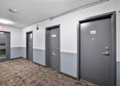 Thumbnail 12 of 53 - a hallway with three doors and a carpeted floor