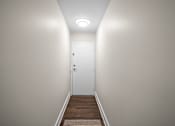 Thumbnail 27 of 53 - a hallway with white walls and a wooden floor with a white door at the end of it