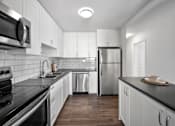 Thumbnail 50 of 53 - a kitchen with white cabinetry and black countertops