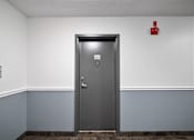 Thumbnail 45 of 53 - a metal door in a gray walled room with a red fire hydrant above it