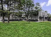Thumbnail 20 of 22 - A grassy area in front of a building with trees.