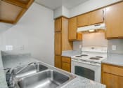 Thumbnail 35 of 46 - a kitchen with a sink and stove and wooden cabinets