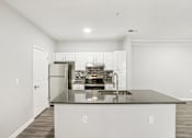 Thumbnail 11 of 35 - A kitchen with a black countertop and stainless steel appliances.